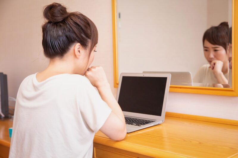 パソコンを見ながら悩む女性